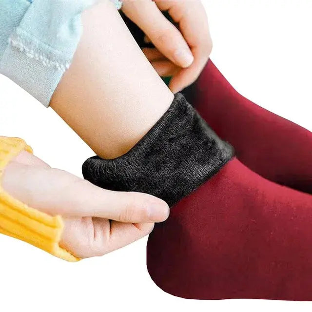 The image features a pair of warm socks in a cozy setting. The socks are designed for extreme cold, capable of withstanding temperatures as low as -30 degrees. Red variant is highlighted. The visual showcases the texture and warmth of the socks, providing a tactile sense of comfort for the wearer during chilly weather.